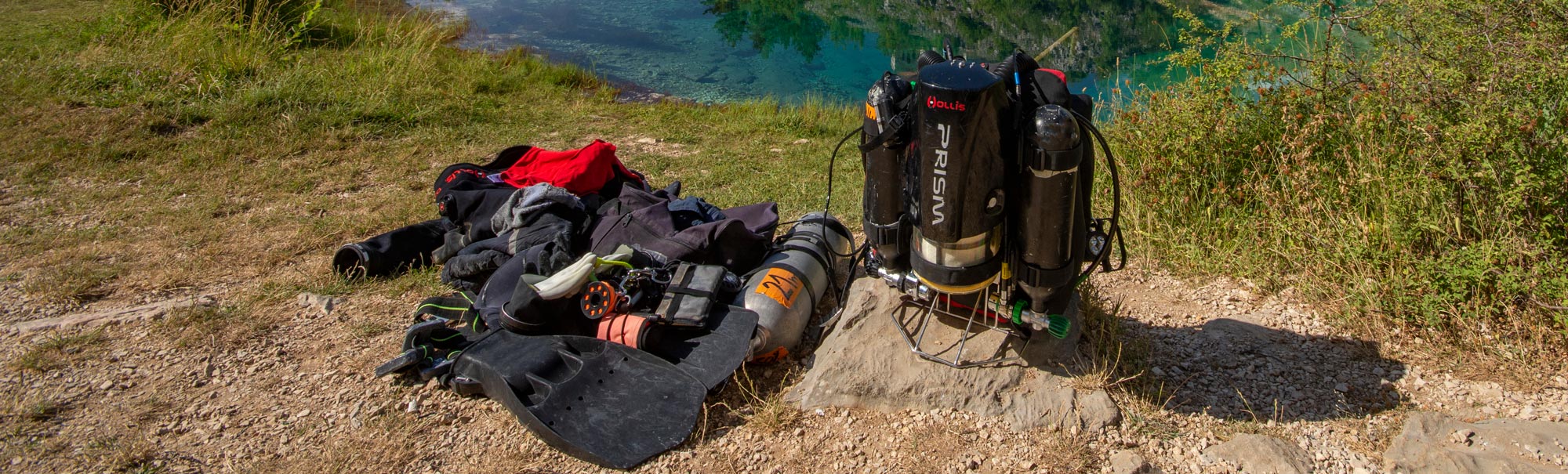 Prism 2 Rebreather and a drysuit placed on a beach next to a lake